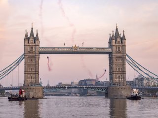 Two people in wingsuits flying through Tower Bridge