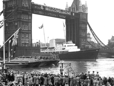Black and white photo of the Royal Yacht Brittania sailing through Tower Bridge