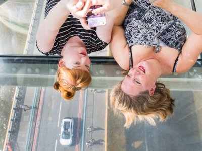 Two visitors lying on the Glass Floor with the road viewable underneath them