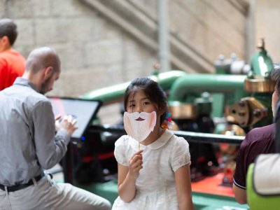 Girl imitates Sir Horace Jones with a paper beard