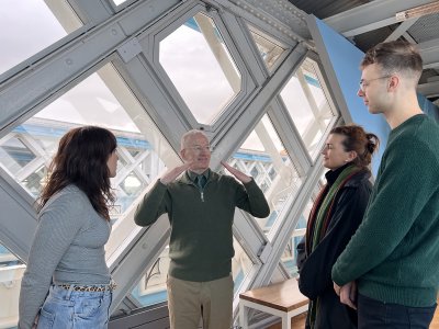 Deaf guide John Wislon signing while visitors stand observing on the High-Level Walkways in Tower Bridge.