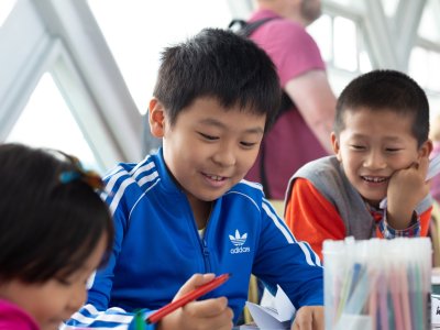 Three children around a table take part in family activities with colouring pens