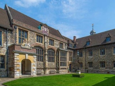 The Charterhouse is a brick building standing in the sunshine with blue skies and green grass.