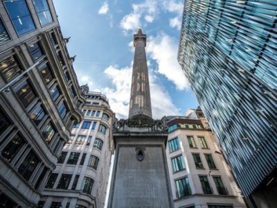 The Monument surrounded by buildings with a blue, cloudy sky.