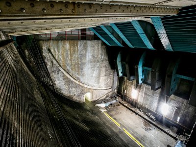 Tower Bridge's Bascule Chamber, a huge stone-lined area with metal work on the ceiling. It is dark and gloomy.