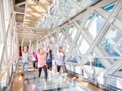A group of people doing yoga on the Glass Floor of Tower Bridge's Walkways