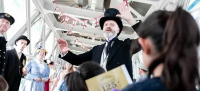 A man in Victorian attire giving a speech to visitors at Tower Bridge