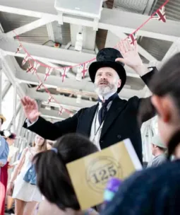 A man in Victorian attire giving a speech to visitors at Tower Bridge