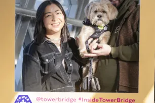 A smiling couple pose with their fluffy dog