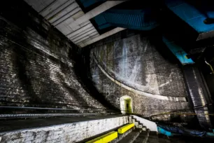 A dark large cavernous space with curved brick stairs.