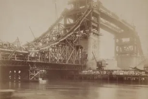 A sephia photo of Tower Bridge being built with it's steel, grid-like structure exposed.