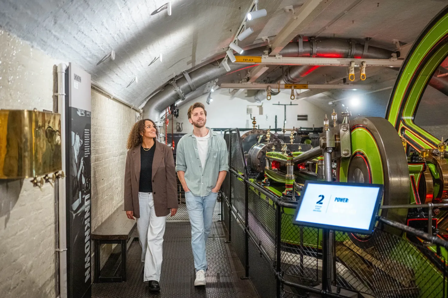 Two visitors looking at green and red steam engines