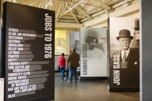 Visitors walking along exhibition displays that showcases previous workers of Tower Bridge