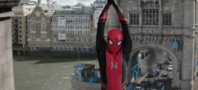 Spiderman dressed in his suit is hanging from Tower Bridge