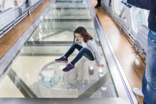 A child sitting on the Glass Floors in the High-Level Walkways at Tower Bridge.