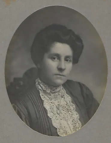 A Victorian black and white portrait of a woman wearing a lacey top and curled hair.