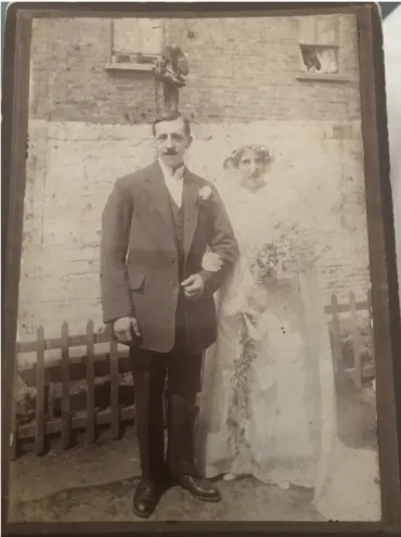 A sepia photo of a couple in wedding attire standing in front of a house.