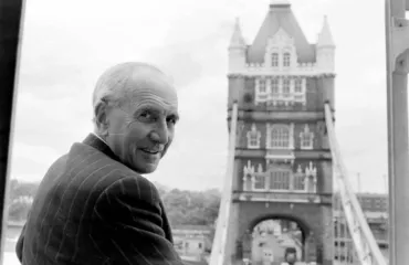 A black and white photo of a man at Tower Bridge