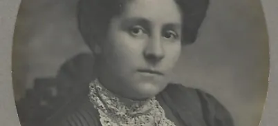 A Victorian black and white portrait of a woman wearing a lacey top and curled hair.