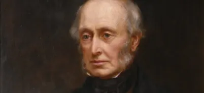 A portrait of an elderly man wearing a Victorian suit and waistcoat. He has sideburns and a bald head.