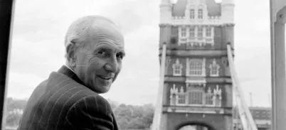 A black and white photo of a man at Tower Bridge