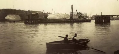 A sephia photo showing a rowing boat in the foreground on the river Thames
