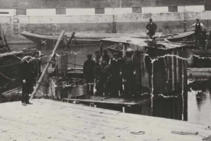 A black and white photo of Victorian divers enterin the caissons