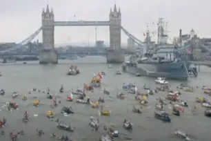 Tower Bridge in London during the large Jubilee river pageant, with numerous decorated boats and the historic HMS Belfast warship on the River Thames as part of a ceremonial flotilla.