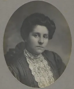 A Victorian black and white portrait of a woman wearing a lacey top and curled hair.