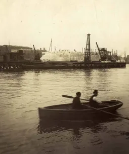 A sephia photo showing a rowing boat in the foreground on the river Thames