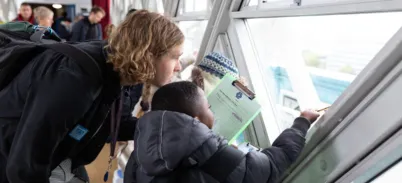 A school teacher and small child look out of the Tower Bridge walkway window.