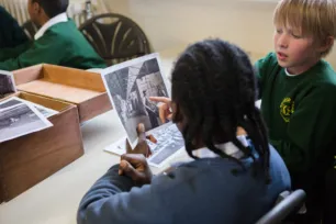Two schoolchildren point at a black and white photo.