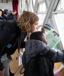 A school teacher and small child look out of the Tower Bridge walkway window.