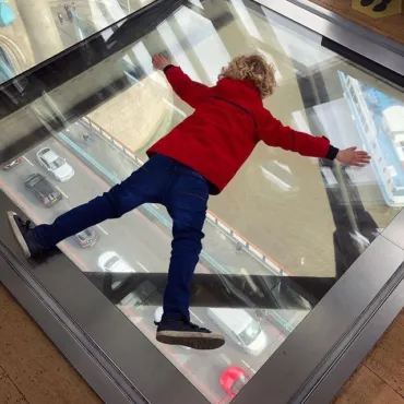 A child on the Glass Floors at Tower Bridge watching traffic underneath.