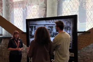 Two visitors and a guide in front of a screen at North Tower level 4