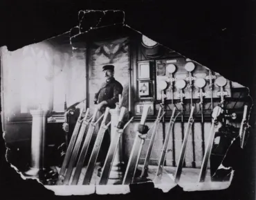 A Bridge Driver standing in the old control room over several large levers in front of dials in the background. The photo is black and white.