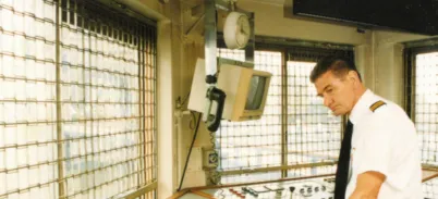 Bill Skinner in the modern Tower Bridge control room standing over a panel of controls and buttons.