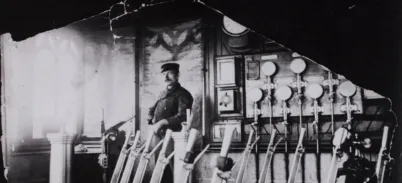 A Bridge Driver standing in the old control room over several large levers in front of dials in the background. The photo is black and white.