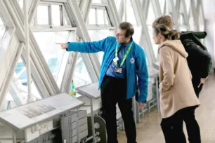 A man who is a welcome host at Tower Bridge assisting visitors on the Walkway