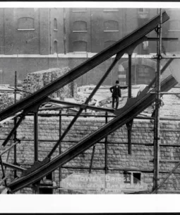 A man standing on suspension chain of Tower Bridge during construction