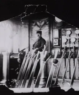 A Bridge Driver standing in the old control room over several large levers in front of dials in the background. The photo is black and white.