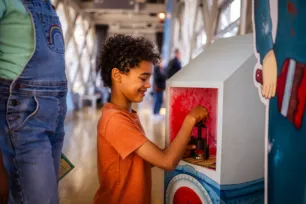 A boy stamping a booklet while he completes the Tower Bridge Cat Trail.