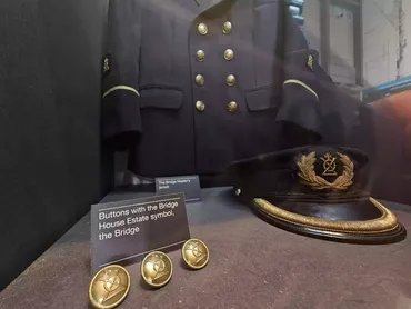 Museum exhibit showing jacket with brass buttons and embroidered peaked cap