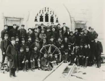 A black and white photo of a group of men outside one of the Towers at Tower Bridge