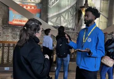 A man in a blue uniform speaking to a visitor