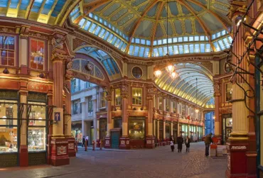 Interior view of Leadenhall Market, showcasing its ornate Victorian architecture with decorative red and gold columns.