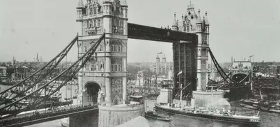 Historic black and white photograph of Tower Bridge with steamboats on the river and crowds on the Bridge
