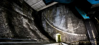 A dark large cavernous space with curved brick stairs.
