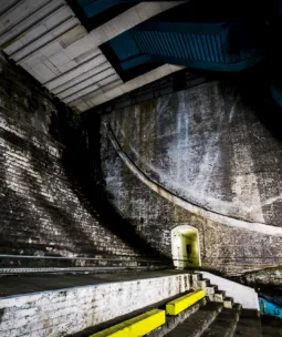 A dark large cavernous space with curved brick stairs.