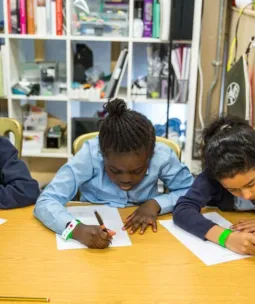 Three school children writing at a desk